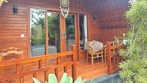 Una baita di legno con un portico, un tavolo con sedie e un decorativo acchiappasogni appeso al soffitto.