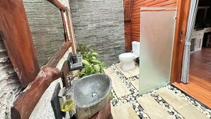 Un bagno piccolo con una parete in pietra, una porta di legno e un lavabo.