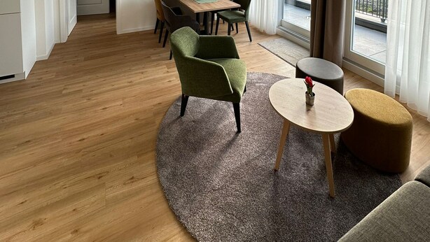 Un amplio salón con vigas de madera, una mesa de comedor, sillas, un televisor y un balcón con vistas.
