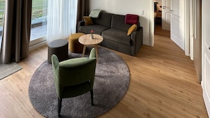 Una sala de estar moderna con techo de madera, un sofá gris, un sillón verde y una mesa de centro redonda.