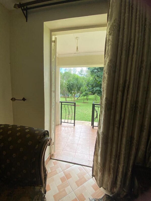 A room with a view of a garden through an open door. - Sungura Farm House (Nairobi)
