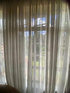 Janela com cortinas leves permitindo a entrada de luz natural no quarto.