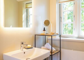 Ein Badezimmer mit einem weißen Waschbecken, einem Spiegel und einem Ablagebereich für Toilettenartikel.
