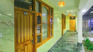Un pasillo con puertas de madera, suelo de mármol e iluminación colgante.