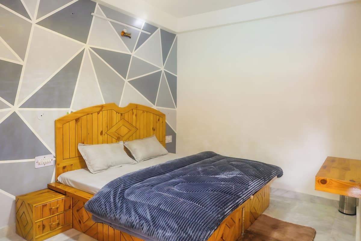 A bedroom with a wooden bed, a geometric-patterned wall, and a ceiling light fixture.