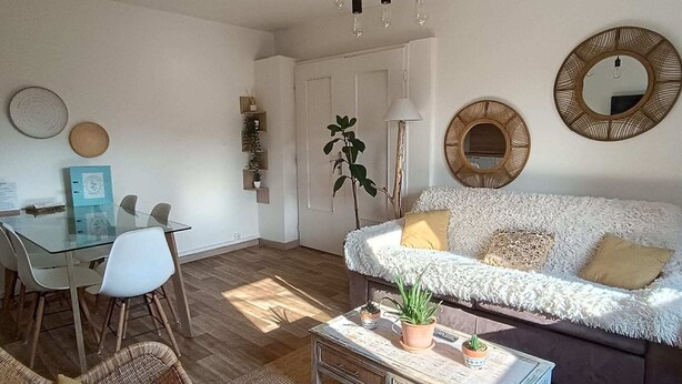 Una sala moderna con una mesa de comedor de vidrio, sofá blanco y espejos decorativos.