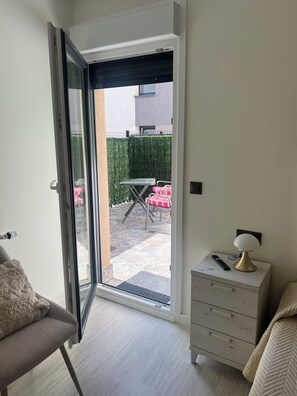 A room with a sliding glass door leading to an outdoor patio with a table and chairs.