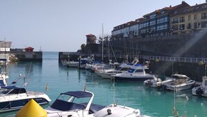 Una marina con barche ormeggiate, un muro in pietra e edifici sullo sfondo.