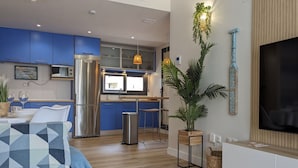A modern kitchen with blue cabinets, stainless steel appliances, and a wooden dining table with a geometric pillow. - CALA ALTA design apartment (Benidorm)