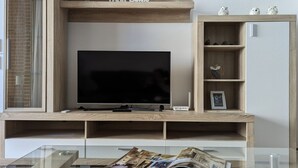 Un salon moderne doté d’un téléviseur à écran plat, d’étagères en bois et d’une table basse en verre.