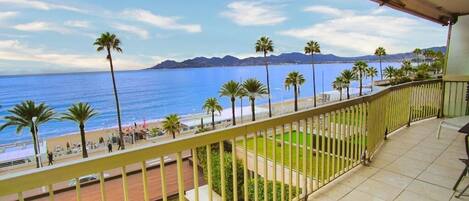 A balcony with a view of the sea and palm trees.