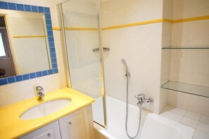 Ein Badezimmer mit einem gelben Waschbecken, einer Duschkabine aus Glas und einer weißen Badewanne.