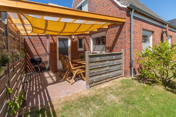 Enjoy al fresco dining under a shaded pergola with a beautifully set table and garden views.