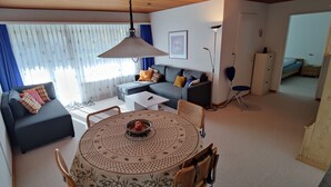 A modern living room with a round dining table, sofas, and a television. - Gemütliches Appartement für Erholung und Sport (Klosters-Serneus)
