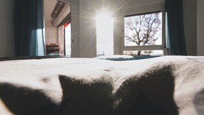 A room with a bed, a window, and a door.
