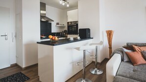 A modern kitchen with a central island, bar stools, and a dining area with a sofa.