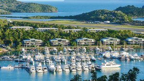 A marina with numerous boats docked, surrounded by lush greenery and hills in the background. - Jasmine house  (Hamilton Island)