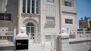 A building with a stone facade, arched entrance, and a gated driveway. - Dali House (Amman)