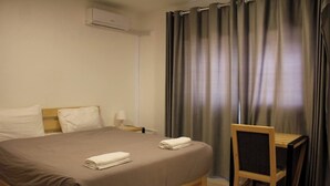A hotel room with a bed, a chair, a nightstand, and a window with curtains. - Dali House (Amman)
