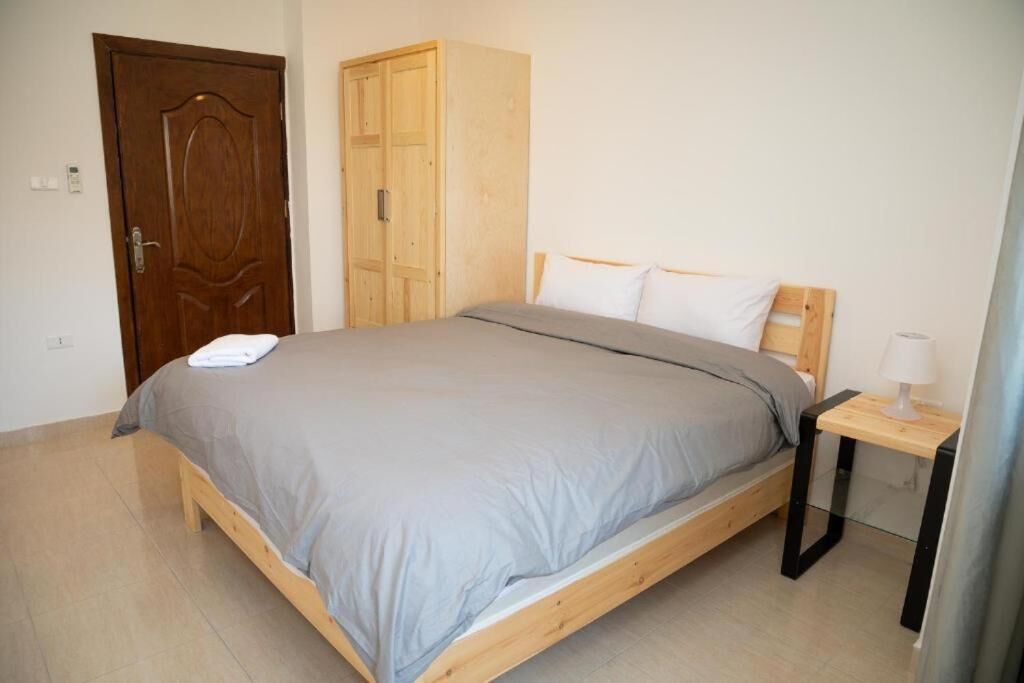 A bedroom with a wooden bed, a wardrobe, and a bedside table with a lamp.