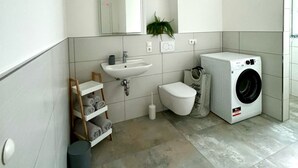 Et moderne badeværelse med vask, toilet og vaskemaskine.