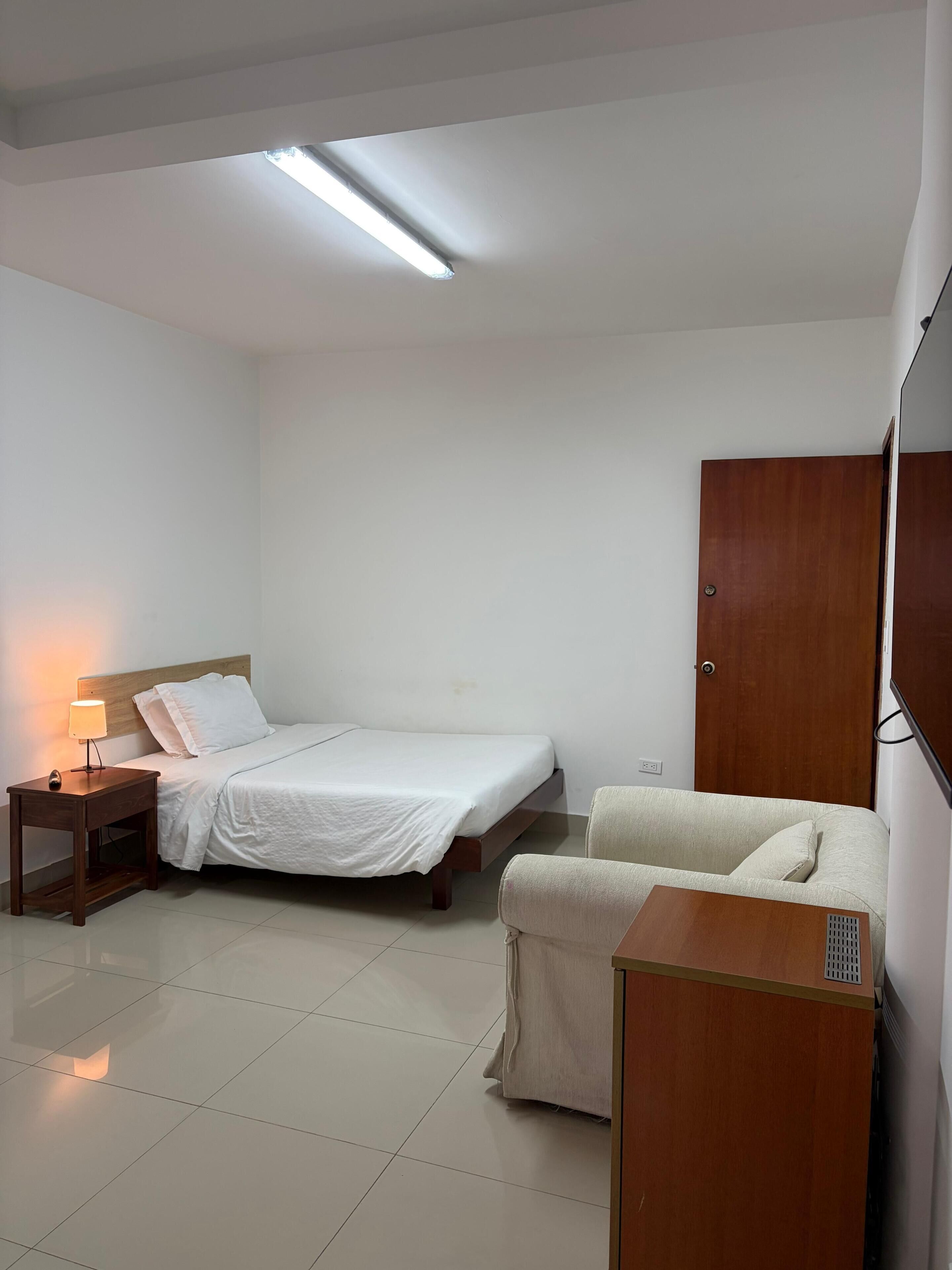 Un dormitorio con cama, mesita de noche, lámpara y armario.