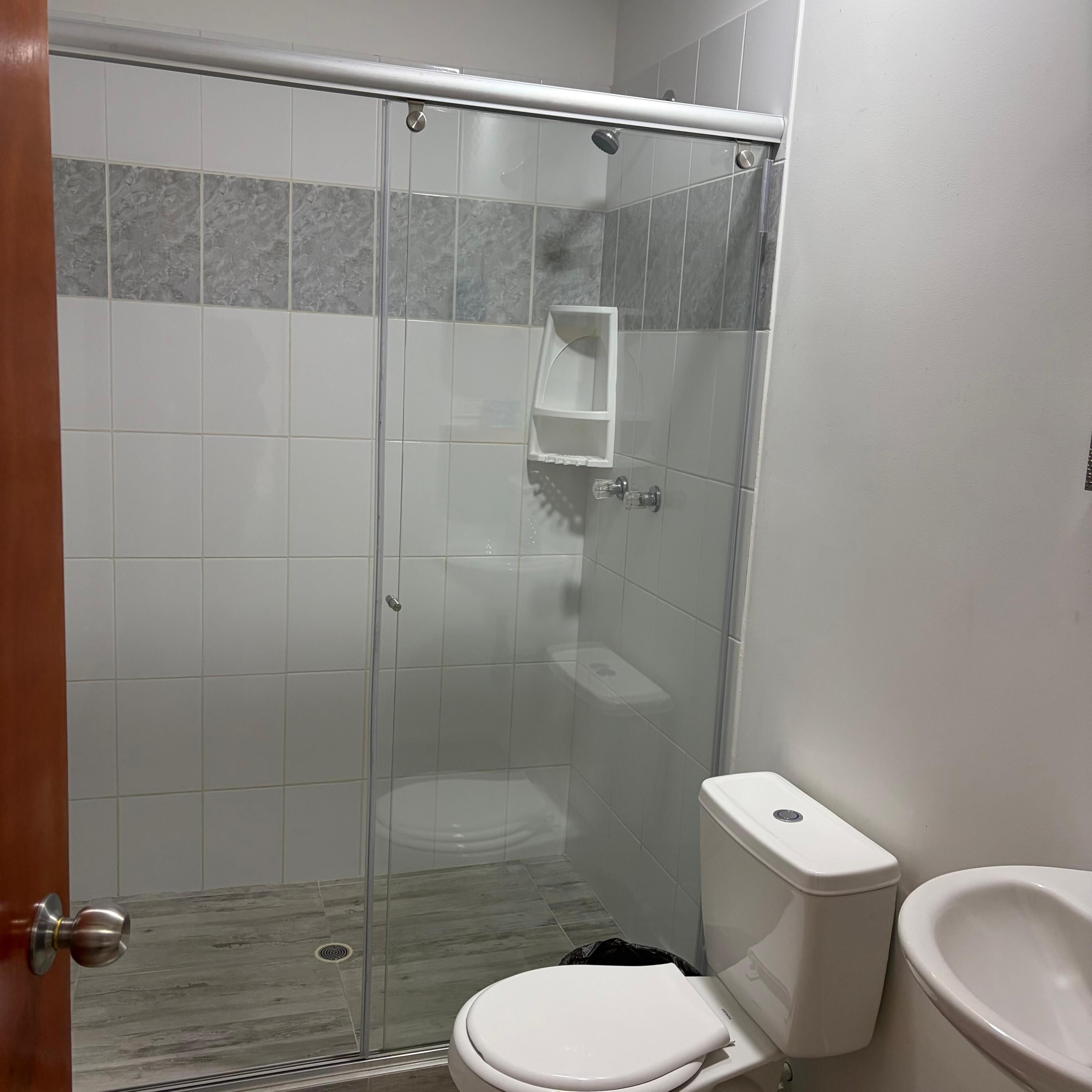 Une salle de bain dotée d’une douche à parois de verre, de toilettes et d’un bidet.