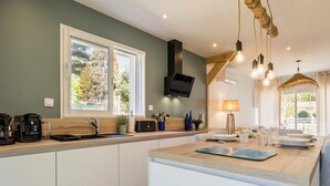 A modern kitchen with a large island, built-in appliances, and a view of the outdoors. - Charming Renovated House Near Beach with Garden & Parking (Saint-Brevin-les-Pins)