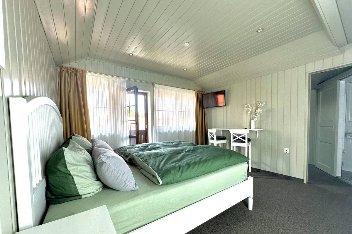 Un dormitorio con cama, escritorio y televisor.