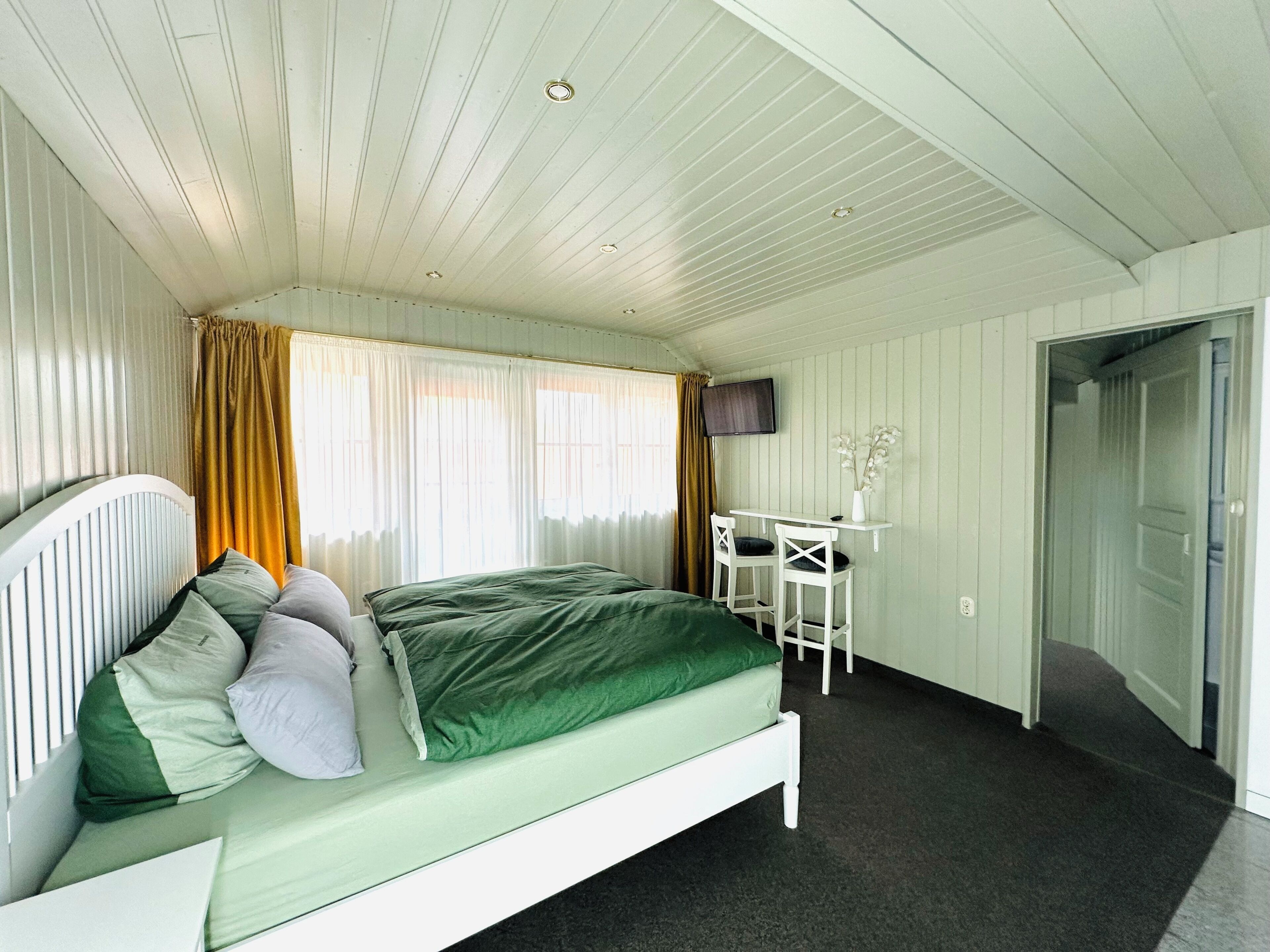 Ein Schlafzimmer mit Bett, Schreibtisch und Fernseher.