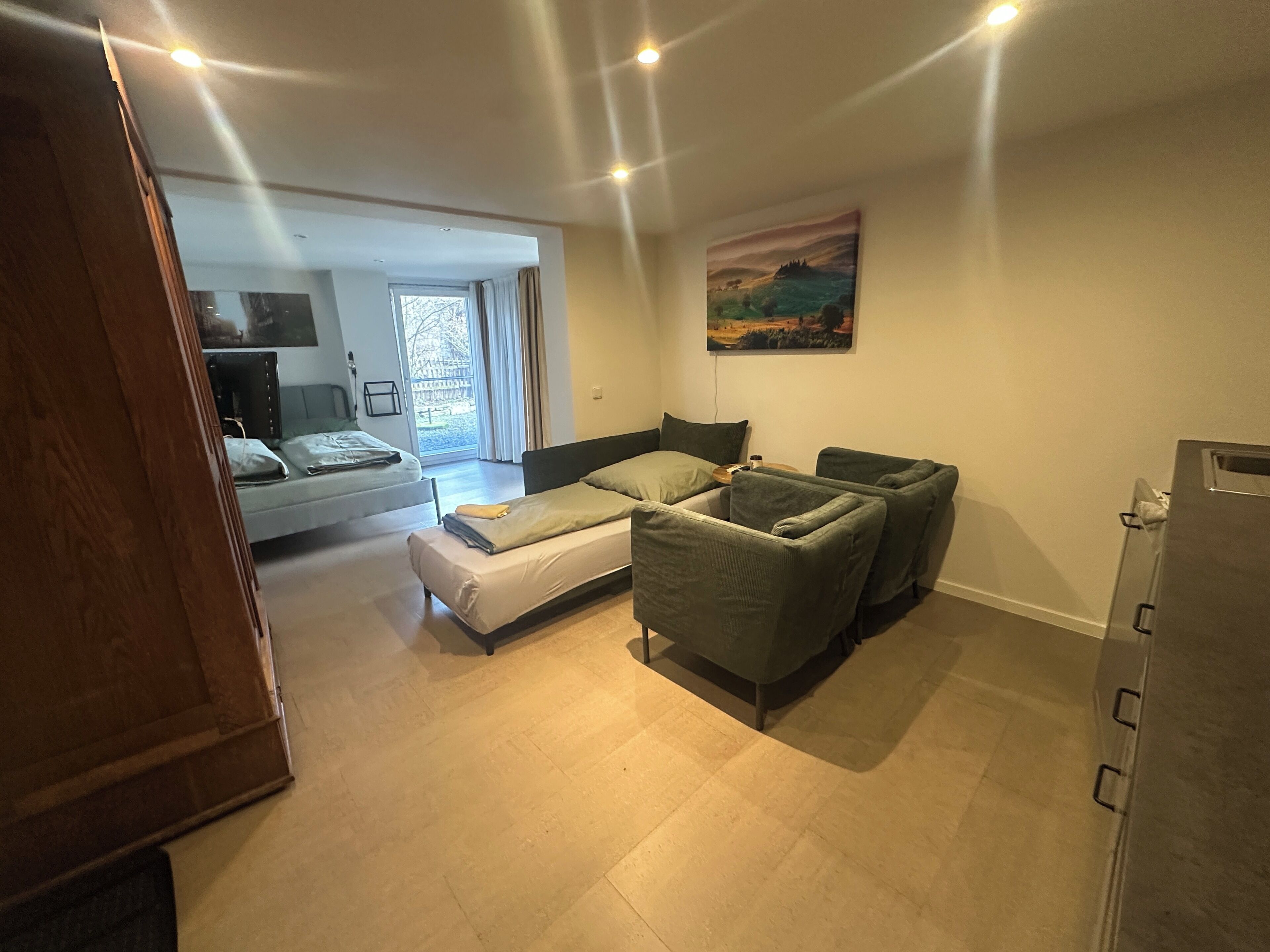 A room with a bed, a sofa, a desk, and a painting on the wall.