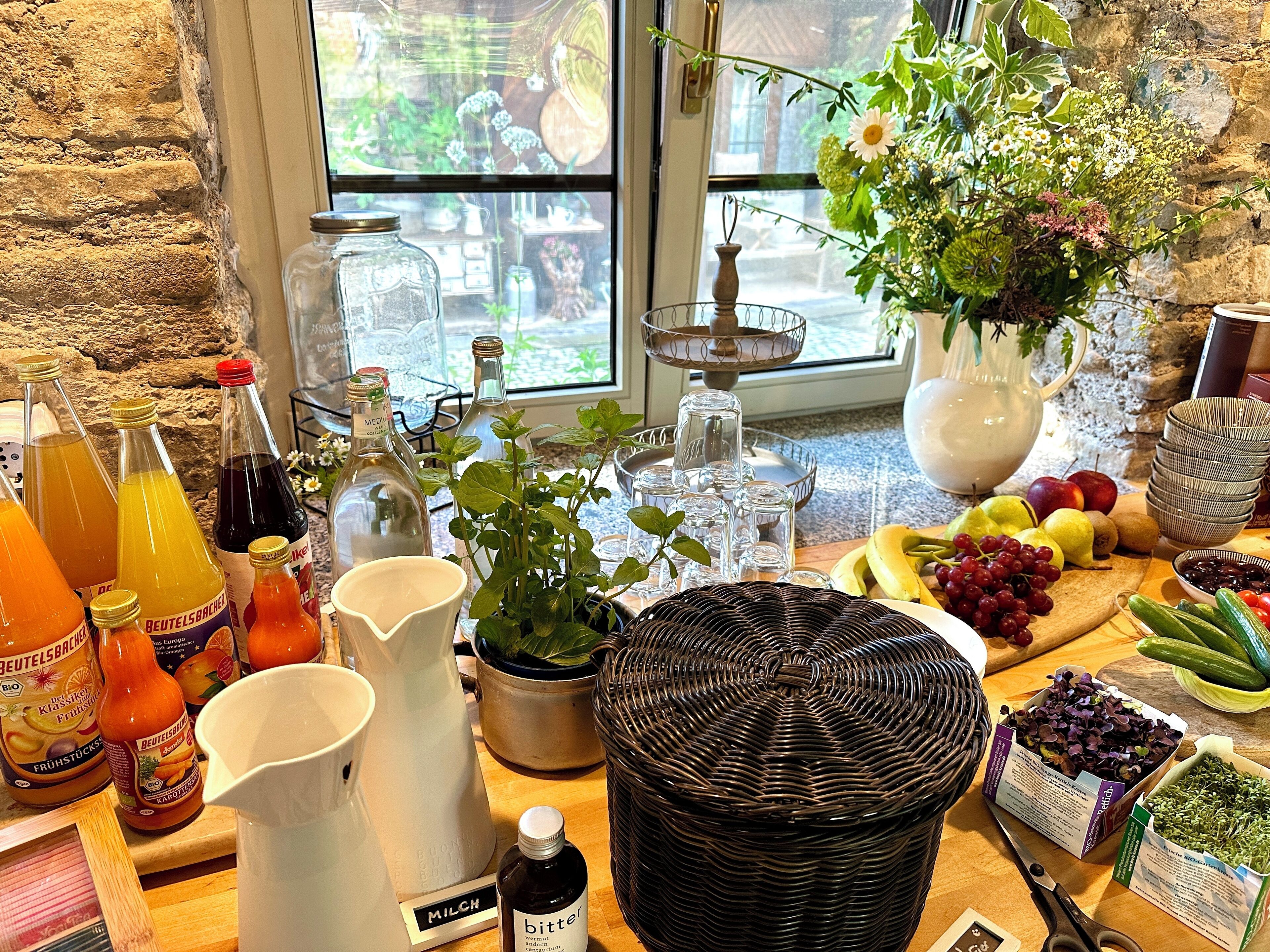 Un comptoir de cuisine avec divers aliments, des bouteilles et une plante en pot.