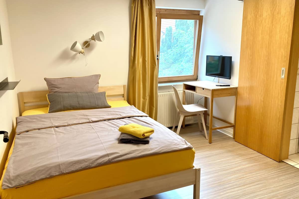 Un dormitorio con cama, escritorio, silla, televisor y armario.