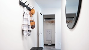 Un pasillo con un perchero, un banco y una puerta que da a una habitación con un tendedero.