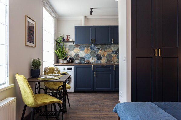 A modern kitchen with dark blue cabinets, a dining area with yellow chairs, and a large window providing natural light.