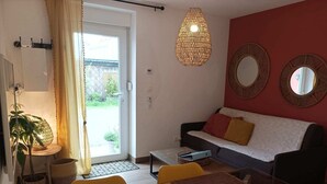 A living room with a sofa, a table, a hanging light fixture, and two wall mirrors.