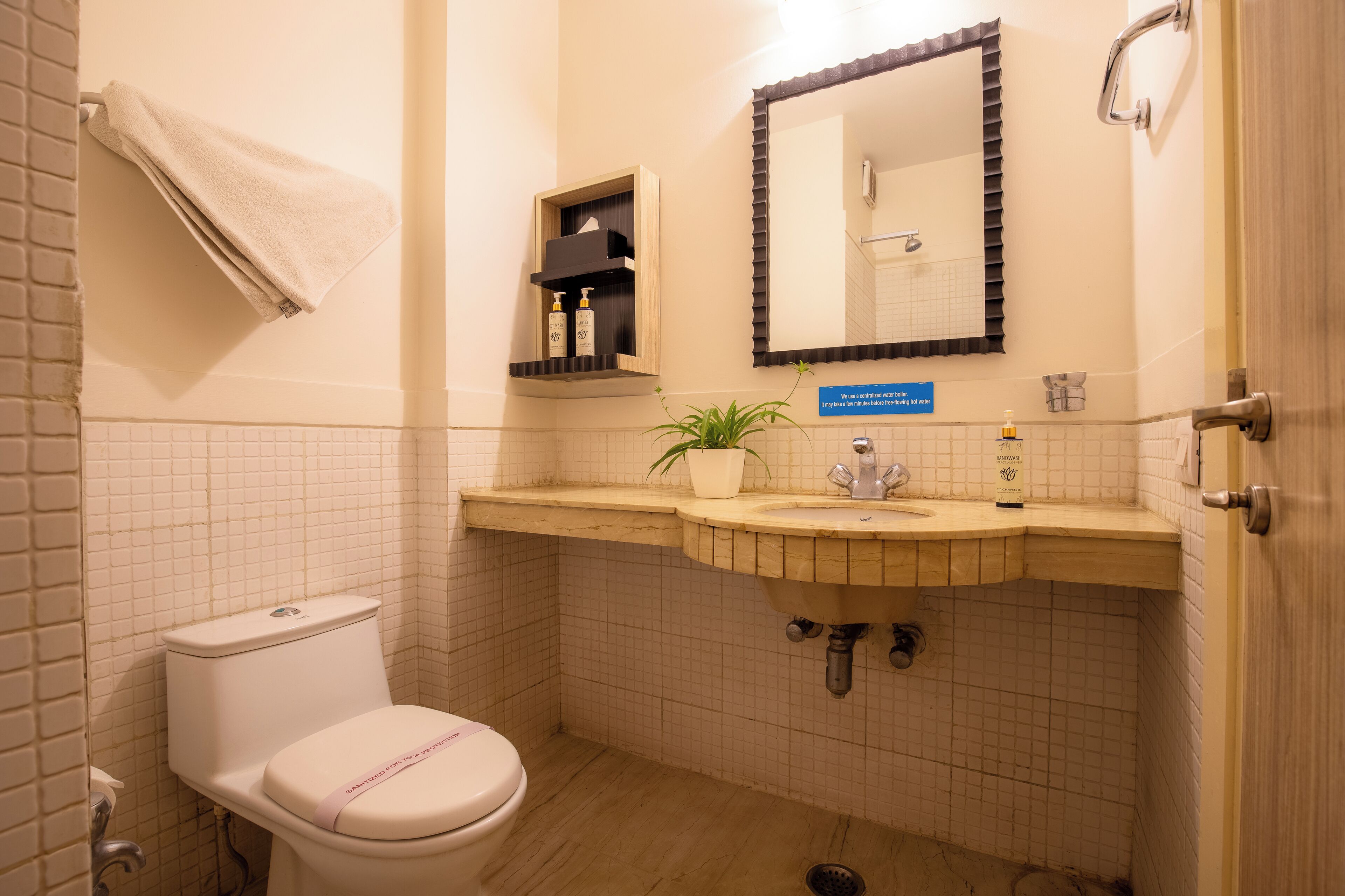 Un baño con inodoro, lavamanos, espejo y toallero.