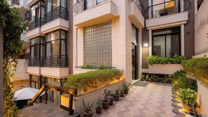 Un immeuble résidentiel à plusieurs étages, doté de balcons, de plantes en pot et d’une cour dallée.