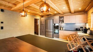Une cuisine moderne avec des poutres en bois, des appareils en acier inoxydable et des luminaires suspendus.
