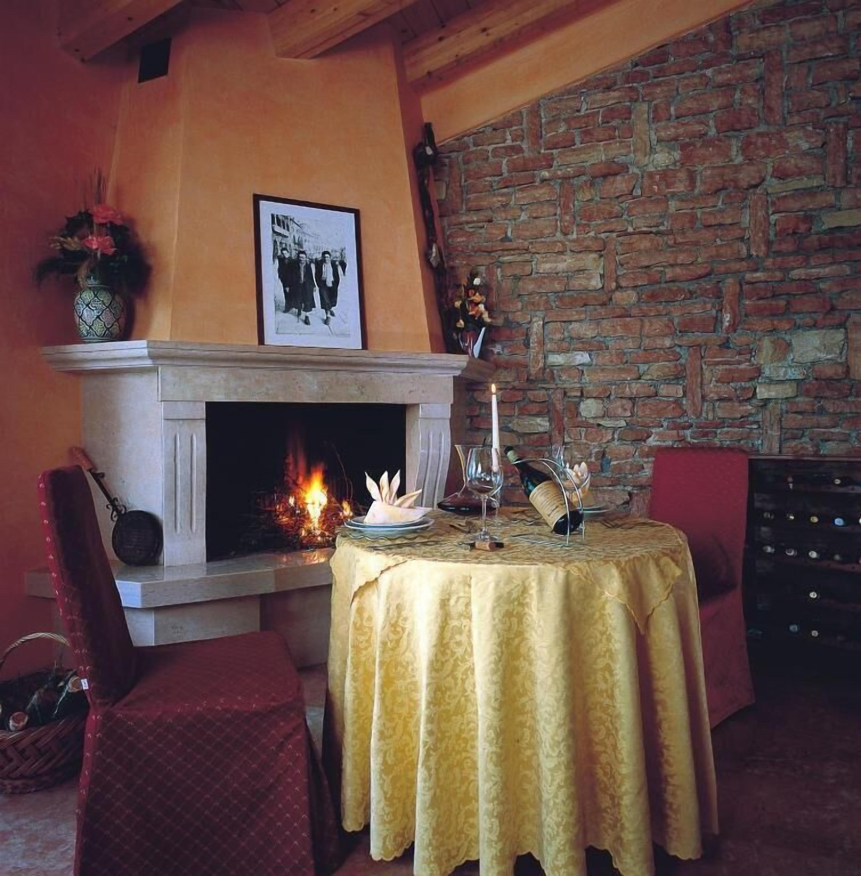 A cozy room with a fireplace, a table set for dining, and a brick wall.