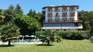 Un hôtel à plusieurs étages doté de balcons, d’une piscine et d’une végétation luxuriante.