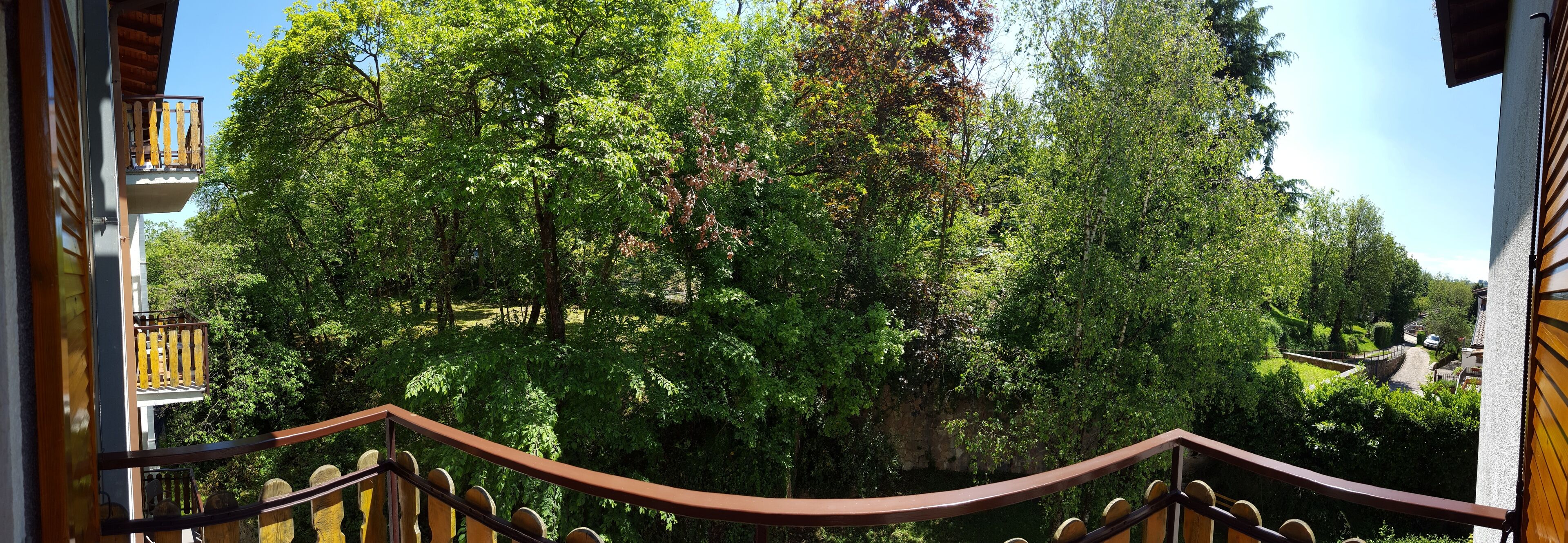 Un balcon donnant sur un jardin luxuriant et un mur de pierre.