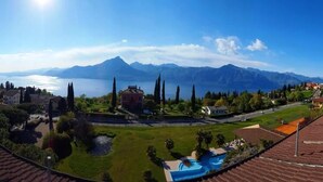 Une vue panoramique d’un complexe hôtelier avec une piscine, une végétation luxuriante et des montagnes en arrière-plan.