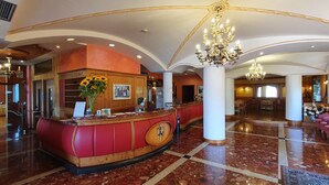 Un hall d’hôtel comprenant un comptoir d’accueil, un lustre et un espace salon.