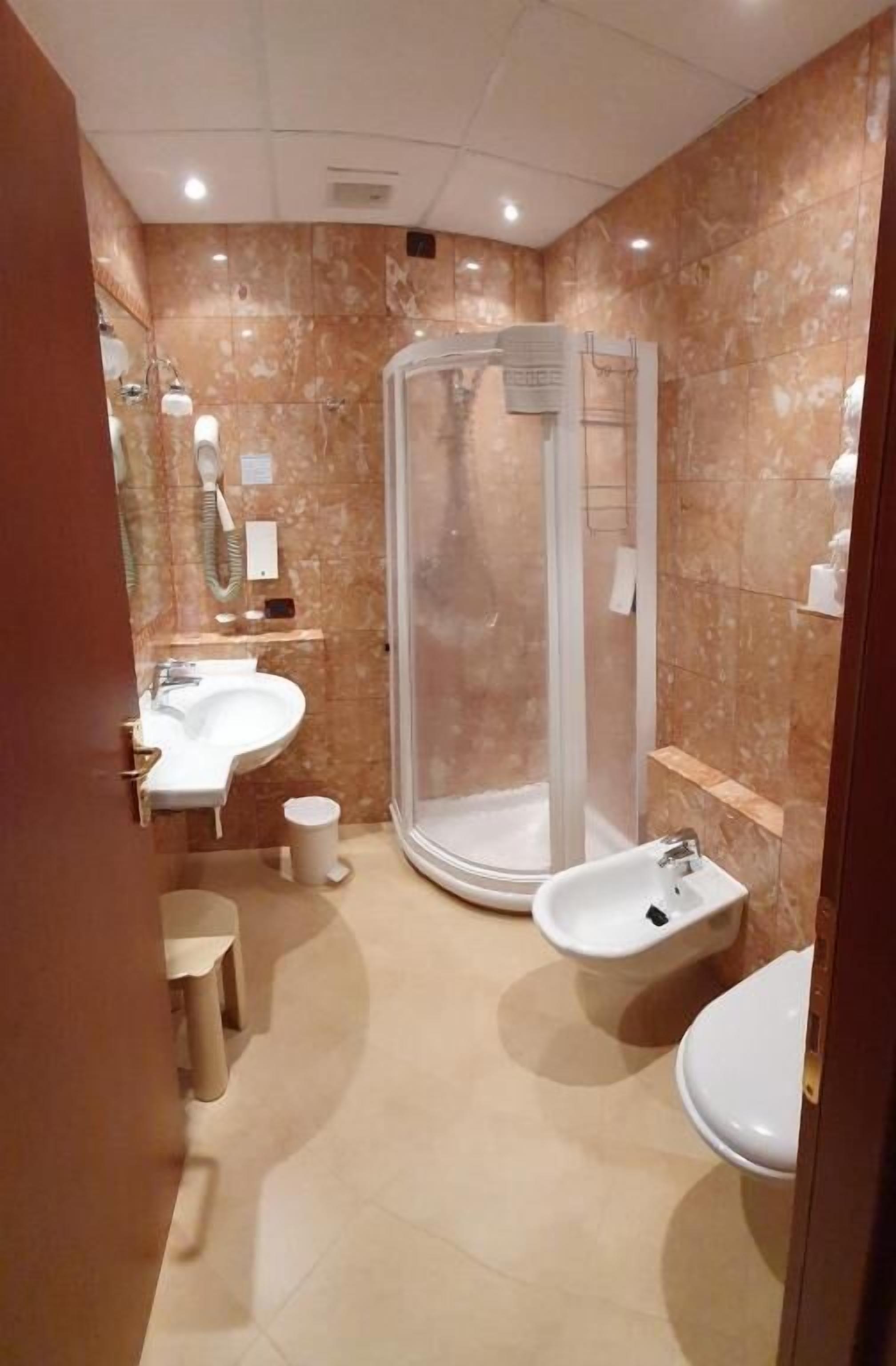 A modern bathroom with a glass-enclosed shower, a sink, and a bidet.