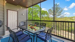 Une terrasse couverte avec une table et des chaises, un ventilateur et une porte.