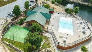 Vue aérienne d’un bâtiment doté d’un toit végétalisé, d’un terrain de basketball et d’un espace piscine avec des chaises longues.