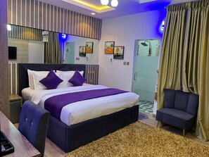 A modern hotel room with a large bed, a desk, and a chair.