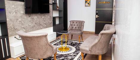 Un salon moderne doté d’un téléviseur à écran plat, de deux fauteuils, d’une table basse et d’un tapis décoratif.