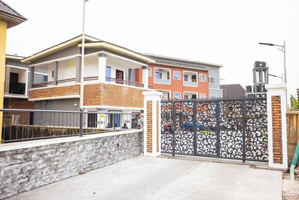 A multi-story residential building with a gated entrance, a balcony, and a brick facade.
